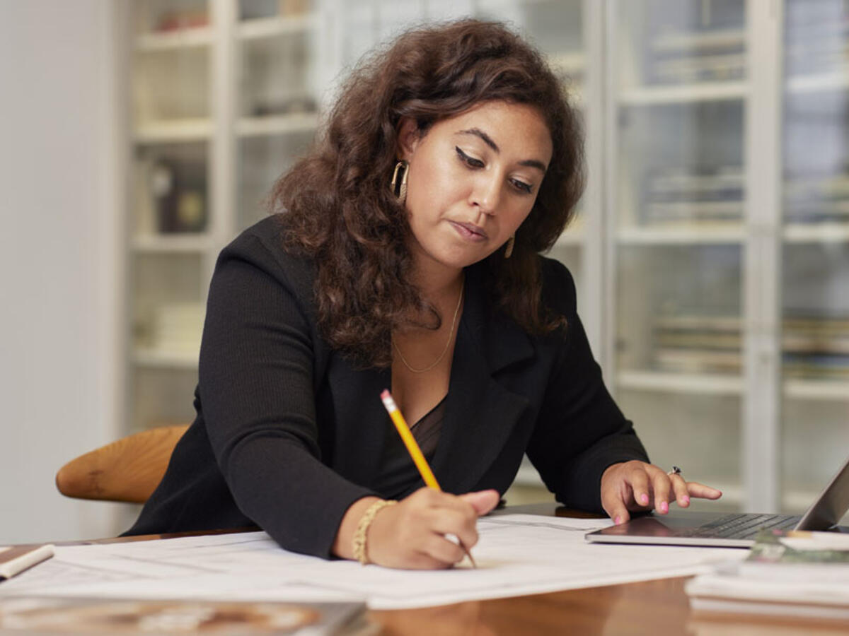 woman writing with a pencil while working in an office environment